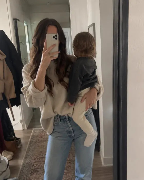 Woman holding a child in a casual home mirror selfie moment